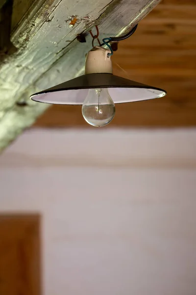 放棄された木造の家の天井に古い電気ランプ 低光量で撮影した写真 — ストック写真