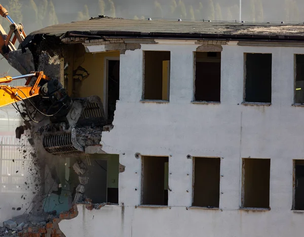 Close up of a bucket of an excavator demolishing an old building. Dangerous demolition works in the city. Photo taken on a sunny day.