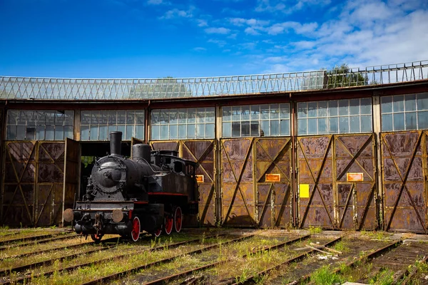 A steam locomotive standing outside of historic locomotive shed. The shot was taken in natural lighting conditions