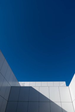 Beyaz, modern bir kamu binasının detayları. Şahıs güneşli bir öğleden sonra mavi gökyüzüne karşı fotoğraflandı.