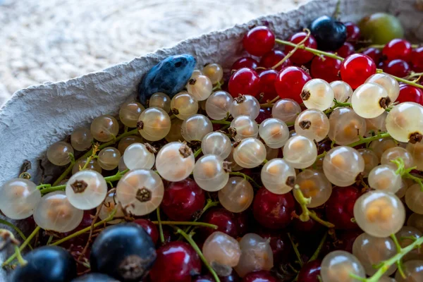 A composition of red, black and white currants in a basket on the background of a mat on the table. Natural, soft light