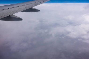 Uçak penceresinden kanada bak. Fotoğraf bulutların üzerinde uçarken çekildi. Uzakta, bulutlardan oluşan görünür bir ufuk.