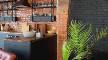 Açık uzay endüstriyel tavan arası mutfağı, gün ışığında klasik dekor ve siyah dolaplar.