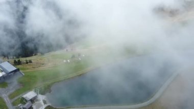 İnsansız hava aracı, Avusturya 'daki Asitz Kogel Dağı' ndaki güzel bir gölün üzerinde süzülen bulutlarla kamerayı çeviriyor, Leogang Saalbach