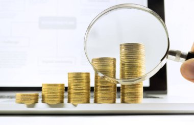 İş büyümesi ve finansal konsept fikirleri için laptop ekranında para yığılı büyüteç ve finansal grafik grafiği..