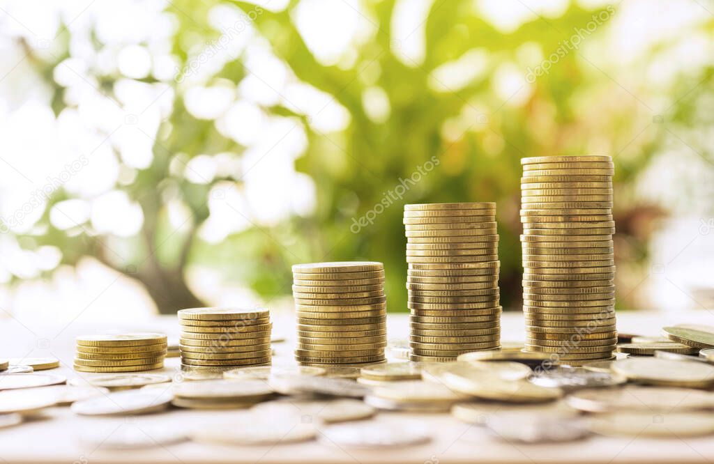 Money coins stack growing with green and sunlight background.For business growth investment and financial concept ideas.
