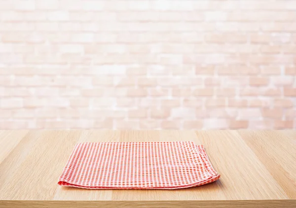 Red fabric,cloth on wood table top on wall background.For montage product display or design key visual layout.