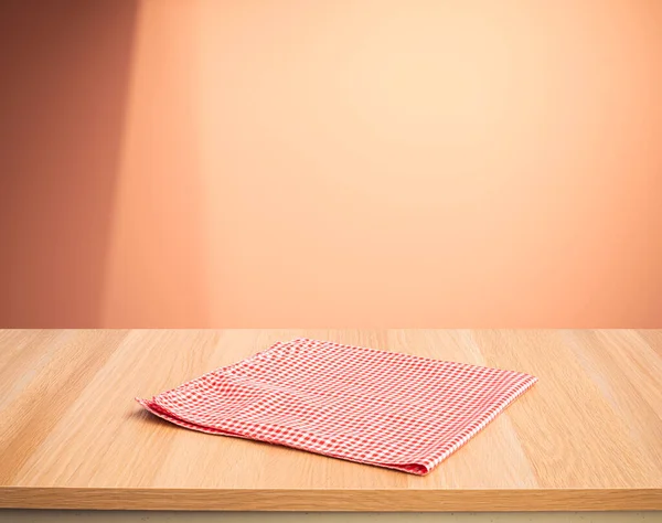 Red fabric,cloth on wood table top on color wall background.For montage product display or design key visual layout.