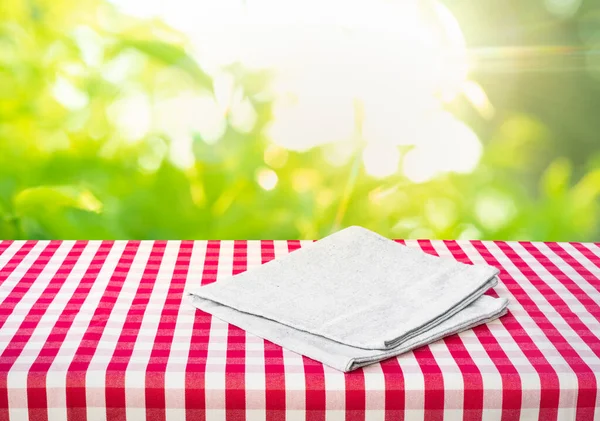 Checked,tablecloth on wood with blur green garden background.Summer and picnic concepts.Design for key visual food and drink