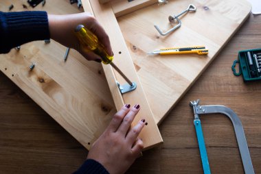 Woman assembly wooden furniture,fixing or repairing house with screwdriver tool.modern living concepts ideas