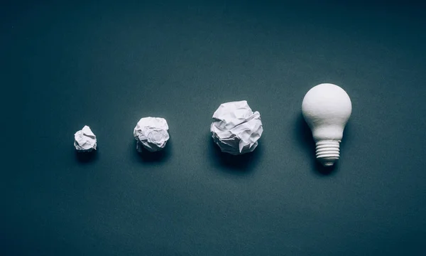 Solution and development ideas concepts with lightbulb and paper crumpled ball on dark background.creativity and inspiration
