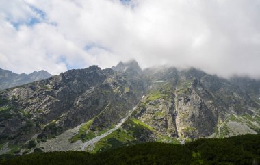 Yüksek Tatras, Slovakya 'da manzara ve bulutlu gökyüzüne karşı kayalık sisli dağlar