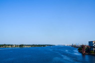 Daugava nehrinde konteynır gemileri ve vinçlerle kargo taşımacılığının sanayi manzarası. Riga, Letonya
