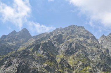 Slovakya 'nın High Tatras kentindeki görkemli yüksek kayalık dağların üzerinde bulutlu gökyüzü ile inanılmaz bir manzara.