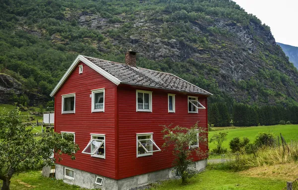 Geleneksel Norveç kırmızı-beyaz ahşap evi Flam 'deki flordun arka planında