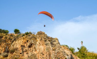 Antalya, Türkiye 'de kayaların üzerinde uçan paraglider. Aktif yaşam tarzı, ekstrem spor. Yaz ve tatil konsepti