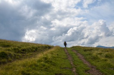 Sırt çantalı gezgin bulutların üstündeki yürüyüş yolunda ufukta geziniyor. Keşif ve macera konsepti