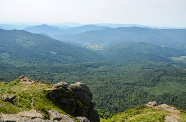Uzakta ormanlık tepeleri ve vadide gökyüzünde bulutları olan güzel yaz manzarası. Karpat Dağları, Ukrayna