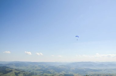 Paraglider açık havada mavi gökyüzüne karşı dağların üzerinden uçuyor. Olağanüstü spor, yaşam tarzı ve özgürlük kavramı