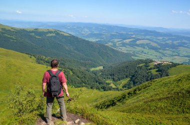 Sırt çantalı bir yürüyüşçü ve dağın tepesinde yürüyüş çubuklarıyla manzaranın tadını çıkarıyor. Karpat Dağları, Ukrayna