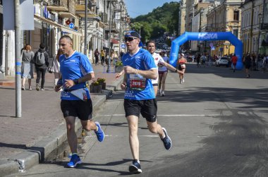 KYIV, UKRAINE - 22 Mayıs 2021: Bir şehir maratonu sırasında sokak yolunda koşan erkek ve kadın sporcular.