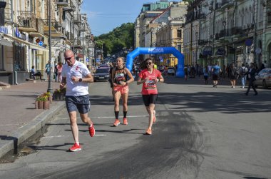 KYIV, UKRAINE - 22 Mayıs 2021: Bir şehir maratonu sırasında sokak yolunda koşan erkek ve kadın sporcular.
