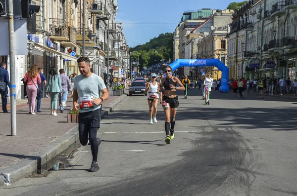 KYIV, UKRAINE - 22 Mayıs 2021: Bir şehir maratonu sırasında sokak yolunda koşan erkek ve kadın sporcular.
