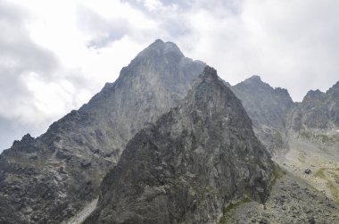 Sisli ve keskin tepeler yukarıdaki sislerin arasından yükseliyor ve Slovakya 'daki High Tatras Ulusal Parkı' nda yağmur bulutları yağıyor.
