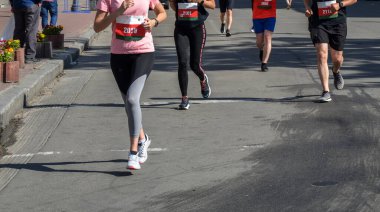 Şehir maratonu sırasında bir grup koşucunun detayları. Bacaklar ve spor ayakkabılar. Stres altındaki kaslar. Spor konsepti