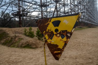 Hayalet kasaba Pripyat ve Çernobil nükleer reaktörü Ukrayna yakınlarındaki Çernobil sınırlama bölgesinde Duga radar kompleksi yakınlarındaki paslı sarı radyoaktif uyarı işareti. 