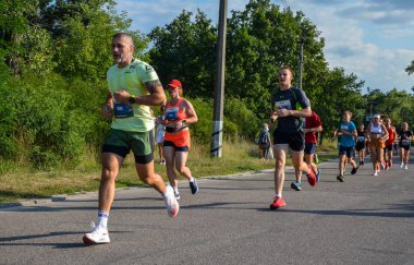 KYIV, UKRAINE - 24 Temmuz 2021: Koşucular açık havada koşuyor. Kentsel alanda yarışan sportif insanlar, sağlıklı yaşam tarzı ve spor kavramları.