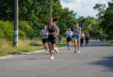 KYIV, UKRAINE - 24 Temmuz 2021: Koşucular açık havada koşuyor. Kentsel alanda yarışan sportif insanlar, sağlıklı yaşam tarzı ve spor kavramları.