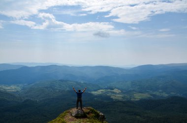 Güzel dağlardaki kayalıklarda dikilen insan yürüyüşçüsünün arka görüntüsü. Yükselen ellerle ve muhteşem manzaranın tadını çıkarırken, yaz zamanı. Karpat Dağları, Ukrayna