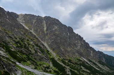 Sisli bir yaz gününde, taşlı, bulutlu ve bulutlu gökyüzüyle inanılmaz doğal bir manzara. Slovakya 'nın Yüksek Tatra Dağları' ndaki dağ zirveleri