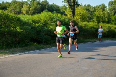 KYIV, UKRAINE - 24 Temmuz 2021: Şehir maratonu sırasında açık havada koşan bir grup genç sporcu. Sokakta spor yapıyor. Sağlıklı yaşam tarzı kavramı.