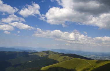Muhteşem bulutların altında kayın ormanları olan otlak tepeler. Karpatlar, Ukrayna 'nın güzel dağ sırtı manzarası 