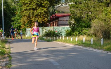 KYIV, UKRAINE - 24 Temmuz 2021: Doğada yazın parkta koşan kız çocuğu. Açık hava sporları ve fitness