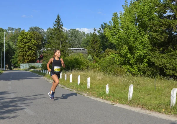 KYIV, UKRAINE - 24 Temmuz 2021: Doğada yazın parkta koşan kız çocuğu. Açık hava sporları ve fitness