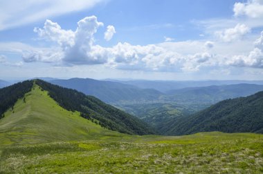 Dağ tepeleri ve çayırlar ile güzel dağ manzarası bulutlu gökyüzünün altında yeşil çimenler ve ormanlar kaplıydı. Karpat Dağları, Ukrayna