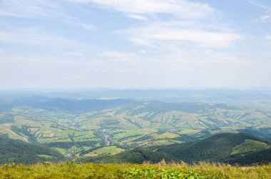 Güzel bir dağ manzarası, doğa arka planı, yeşil çayır vadisi ve pitoresk bir köy. Karpat Dağları. Seyahat ve aktif tatil kavramı