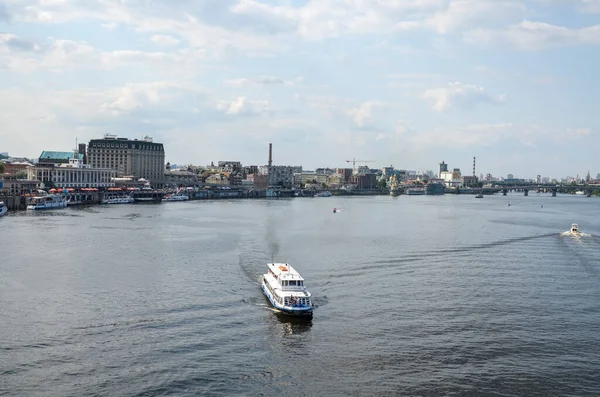 KYIV, UKRAINE - 24 Temmuz 2021: Bir yaz günü Dnipro nehri boyunca setin arka planına ve Podil şehrinin eski kısmına karşı bir zevk gemisi yelken açar. Kyiv, Ukrayna