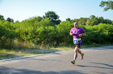 KYIV, UKRAINE - 24 Temmuz 2021: Doğada koşan atletik genç adam. Dinamik hareket. Kentsel sağlıklı aktif yaşam tarzı.