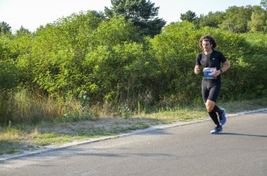 KYIV, UKRAINE - 24 Temmuz 2021: Doğada koşan atletik genç adam. Dinamik hareket. Kentsel sağlıklı aktif yaşam tarzı.