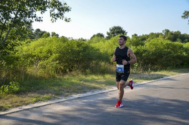 KYIV, UKRAINE - JULY 24, 2021: Athletic young man running in the nature. Dynamic movement. Urban healthy active lifestyle.