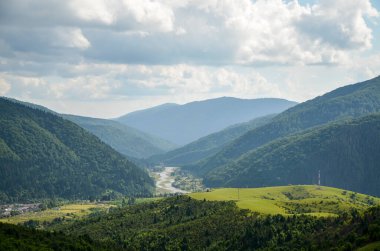 Orman, çayır, nehir ve köyle kaplı yeşil dağlarla kaplı kırsal alan. Karpatlar, Ukrayna.