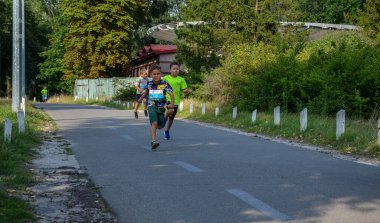 KYIV, UKRAINE - 24 Temmuz 2021: Çocuklar şehir parkında açık pistte koşuyorlar. Çocuklar için sağlıklı spor aktiviteleri. Atletizm yarışındaki küçük çocuklar. Eğitimdeki genç bir atlet. Çocuk için koşmak.