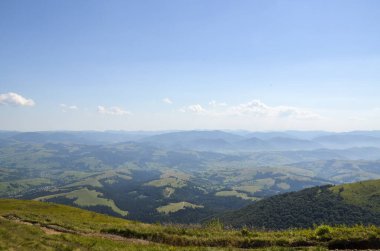 Güneşli bir yaz gününde dağlardan vadiye kadar uzanan güzel kırsal alanlar yeşil tepeler, çimenli çayırlar, orman ve köyler. Karpatlar, Ukrayna