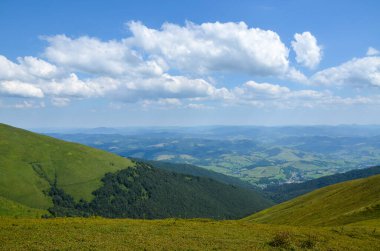 Güneşli bir yaz gününde dağlardan vadiye kadar uzanan güzel kırsal alanlar yeşil tepeler, çimenli çayırlar, orman ve köyler. Karpatlar, Ukrayna