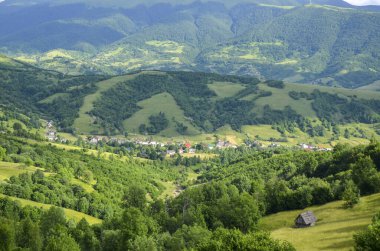 Yeşil çayırları ve Karpat Dağları 'ndaki küçük bir köyü olan renkli bir manzara. Dağ kırsalının en üst manzarası. Kolochava, Transcarpathian, Ukrayna