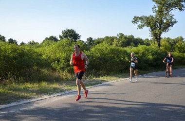 KYIV, UKRAINE - 24 Temmuz 2021: yaz parkında asfalt yolda koşan aktif sporcu erkek ve kadın. Sağlıklı yaşam tarzı kavramı